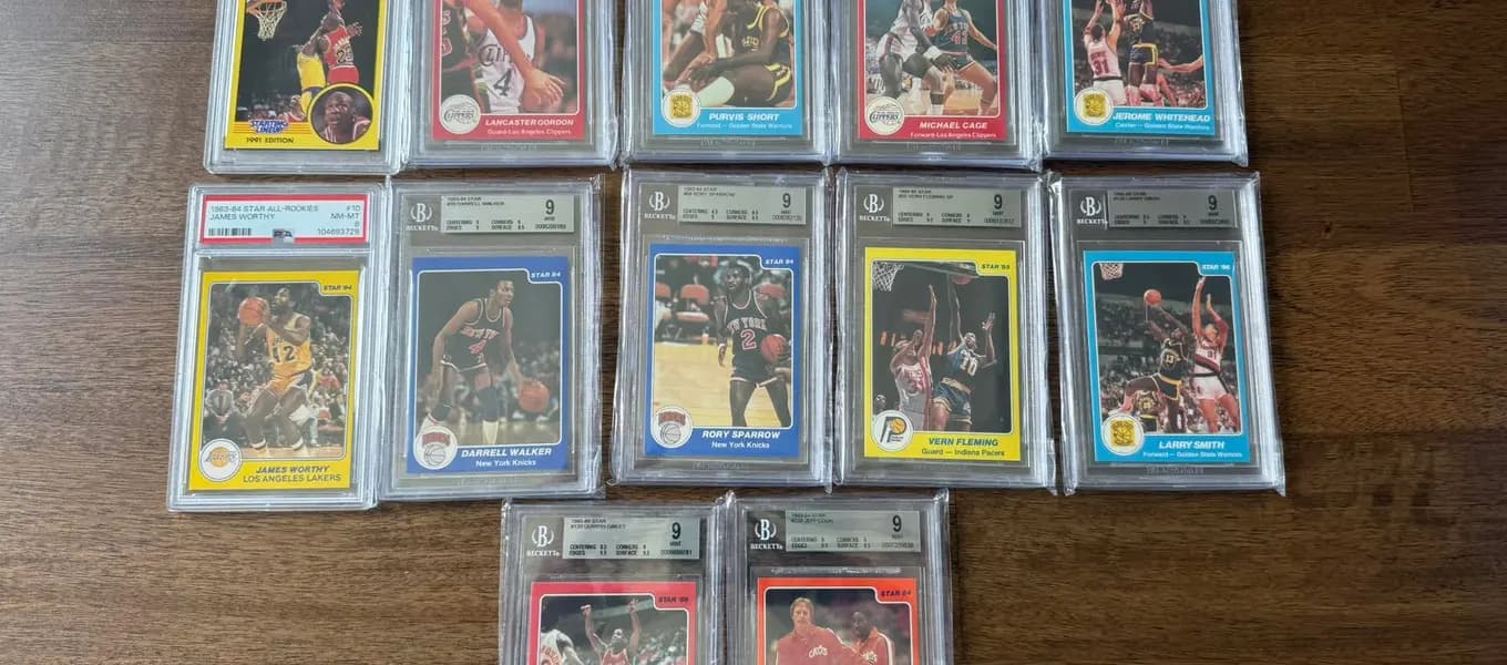 A row of mid-1980s Star basketball cards in Beckett 9 slabs, including a PSA 8 James Worthy, laid out on a wood table