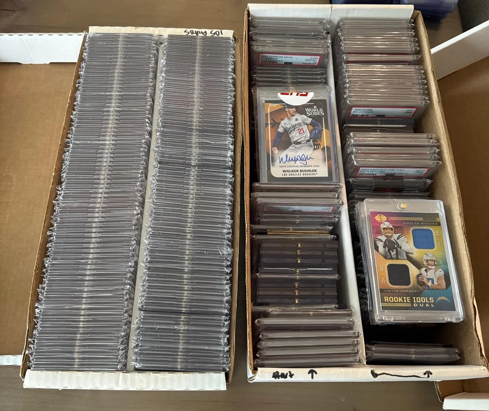 Two boxes filled with graded card slabs, including a Walker Buehler autograph and a Philip Rivers and Justin Herbert dual relic card
