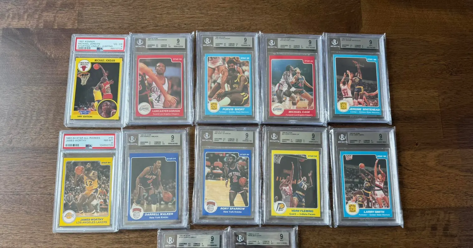 Rows of graded basketball card slabs on a wood table, mostly Beckett 9 Mint 1980s Star cards, with a PSA 4 Michael Jordan Starting Lineup and a PSA 8 James Worthy